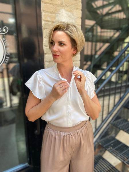 Elevate your wardrobe with the Astra Off-White Satin Button Down Blouse. This versatile button-down top is perfect for any occasion, bringing a touch of sophistication to your style. Whether you're at the office or out for a casual brunch, this blouse keeps you looking effortlessly chic. 

- Luxurious satin finish for a polished look 
- Classic button-down design for versatility 
- Perfect for layering or wearing on its own 
- Easy to dress up or down 
