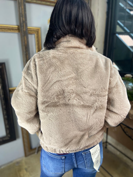 Back view of cocoa colored fur jacket paired with blue jeans