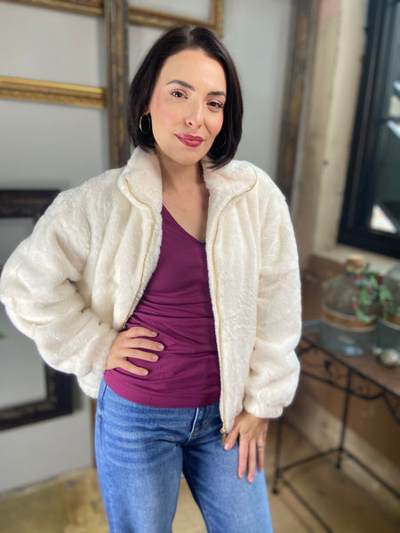 Unzipped Ivory Fur Jacket over a purple tank paired with blue jeans