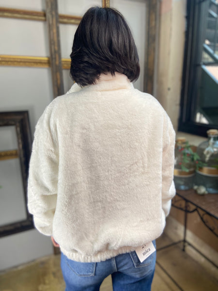 Back view of an ivory fur jacket paired with blue jeans