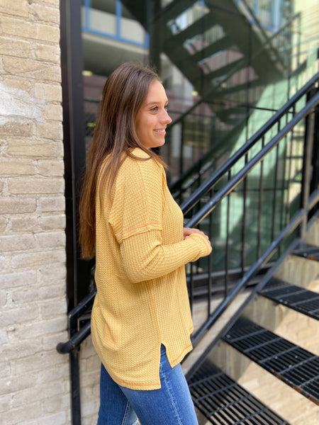 Side view of a mustard colored waffle knit top