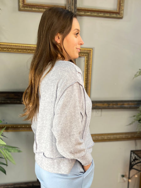 Side view of a Heather gray brushed hacci knit long sleeve top with exposed seams