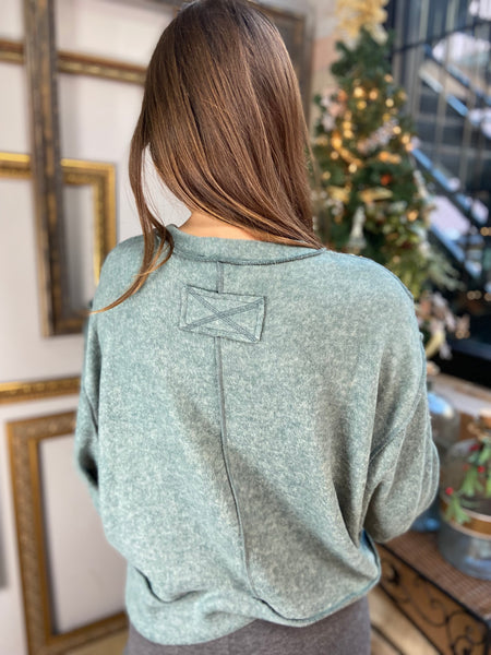 Back view of a light jade colored brushed hacci knit top with long sleeves and exposed seams