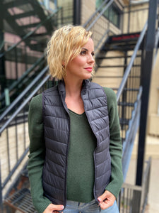 black unzipped puffer vest under a hunter green sweater