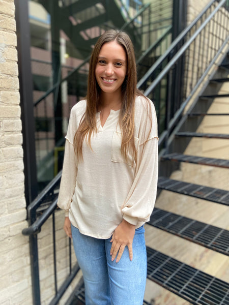 Cream colored V neck top with a front chest pocket from Bibi