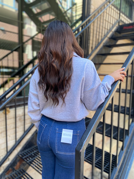 Back view of a heather grey half zip fleece sweatshirt paired with blue jeans