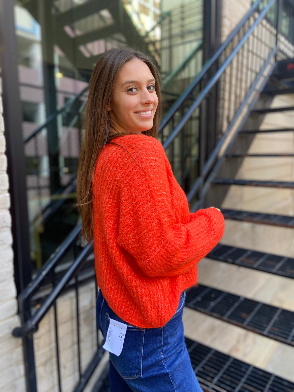 Side view of bright orange sweater paired with blue jeans