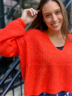 Close up view of a bright orange v neck sweater
