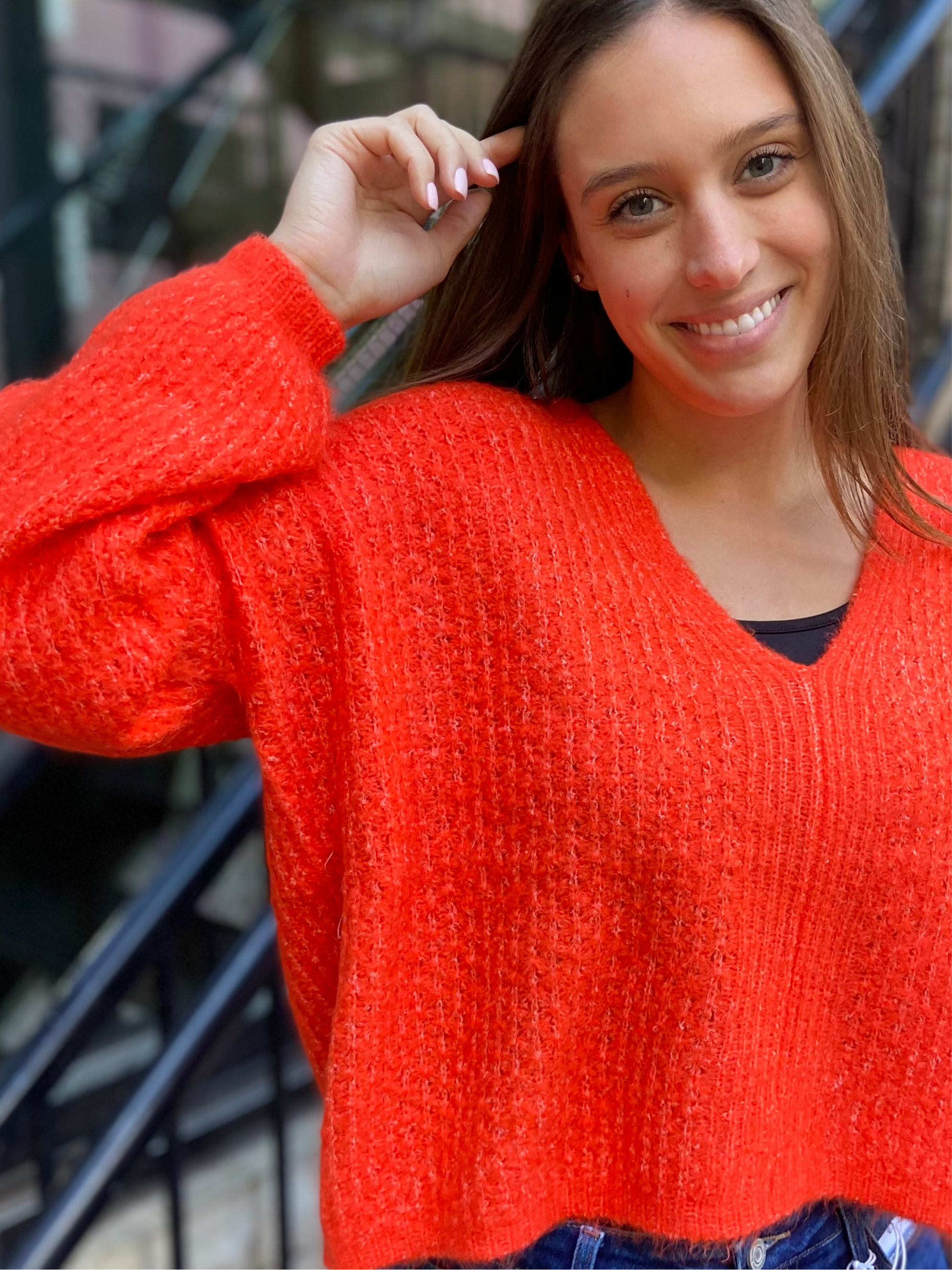 Close up view of a bright orange v neck sweater