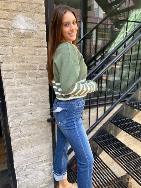 Side view of green & Ivory Striped sweater with blue jeans