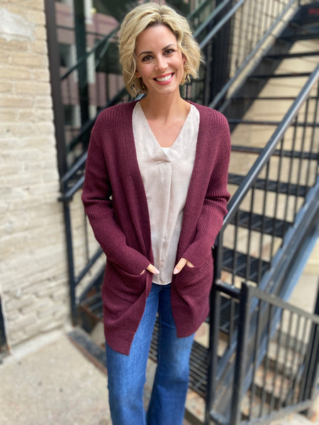 Burgundy colored cardigan sweater paired with blue jeans