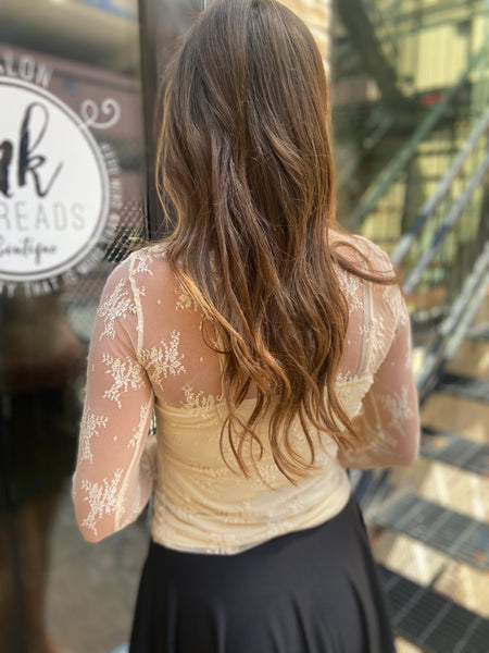 Back view of a beige colored sheer lace floral top