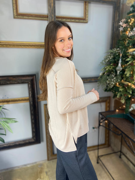 Side view of an oatmeal colored hi low long sleeve top with drop shoulders