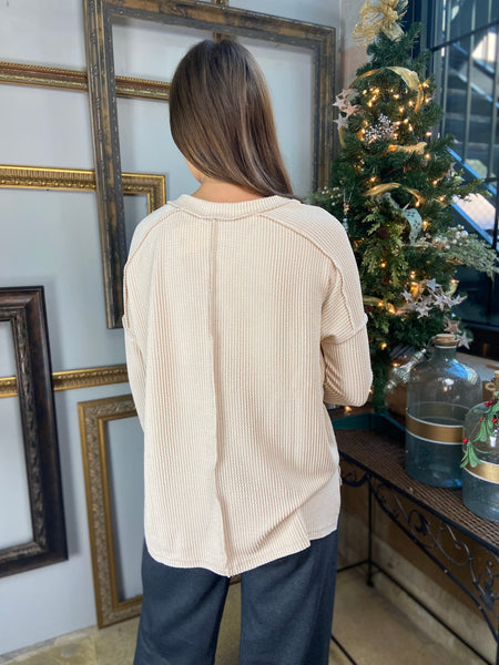 Back view of an oatmeal colored hi low long sleeve top with drop shoulders