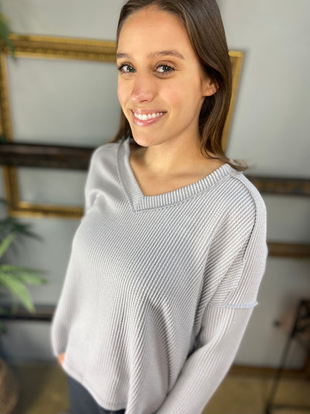 Close up view of a silver colored V Neck long sleeved top with drop shoulders