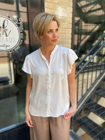 Elevate your wardrobe with the Astra Off-White Satin Button Down Blouse. This versatile button-down top is perfect for any occasion, bringing a touch of sophistication to your style. Whether you're at the office or out for a casual brunch, this blouse keeps you looking effortlessly chic. 

- Luxurious satin finish for a polished look 
- Classic button-down design for versatility 
- Perfect for layering or wearing on its own 
- Easy to dress up or down 
