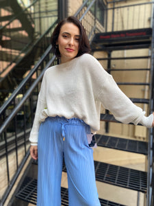 White long sleeved sweater paired with blue dress pants