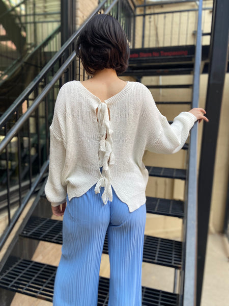 Back view of a white long sleeve sweater with 4 self ties for closure