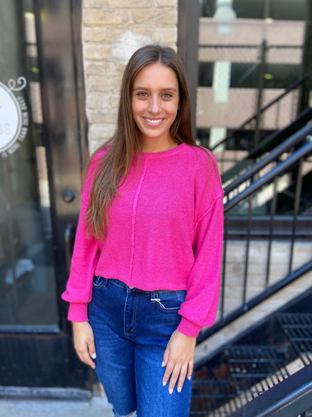 fuchsia textured sweater with exposed seams and drop shoulders paired with blue jeans