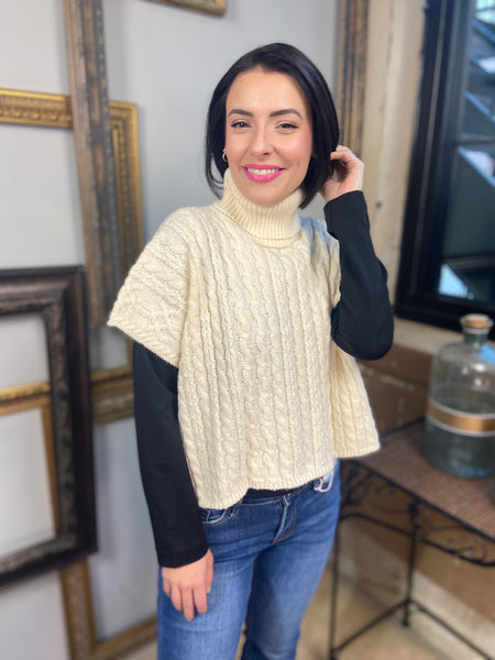 A cream colored short sleeved cable knit sweater with turtle neck from Blu Pepper over a long sleeve black tee