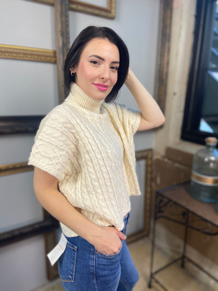 A cream colored short sleeved cable knit sweater with turtle neck from Blu Pepper with blue jeans