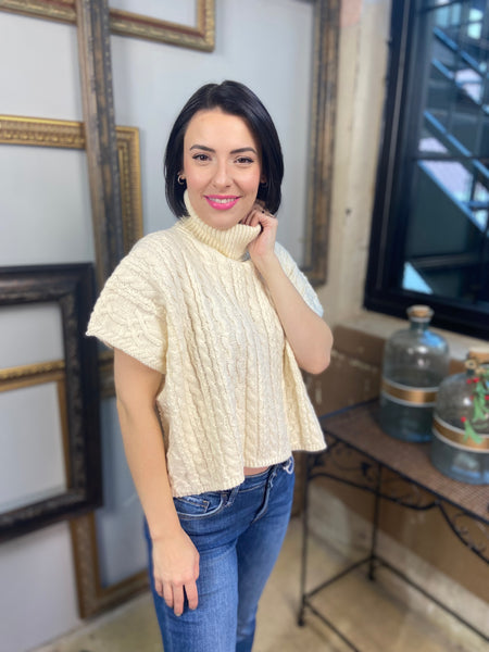 A cream colored short sleeved cable knit sweater with turtle neck from Blu Pepper