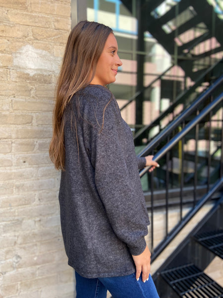 Side view of a brushed knit charcoal colored henley style sweater