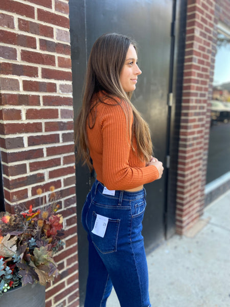 Side view of a rust colored fitted long sleeved cropped top