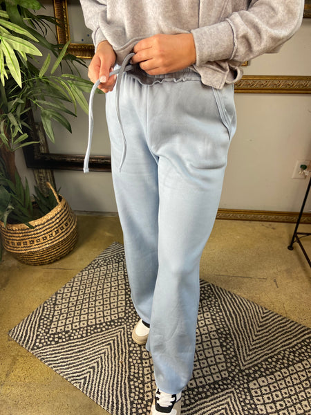 Pair of light blue fleece lined drawstring sweatpants with pockets and wide legs