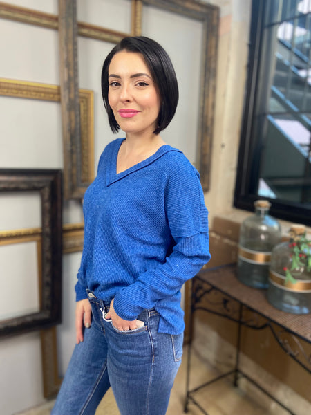 A blue colored v neck long sleeve top from Zenana with exposed seams paired with blue jeans