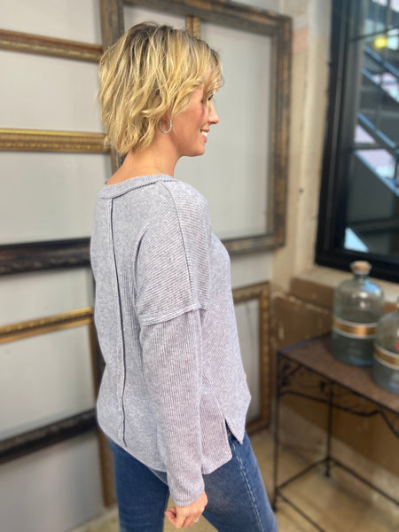 Sde view of a heather grey v neck long sleeve top with exposed seams from Zenana