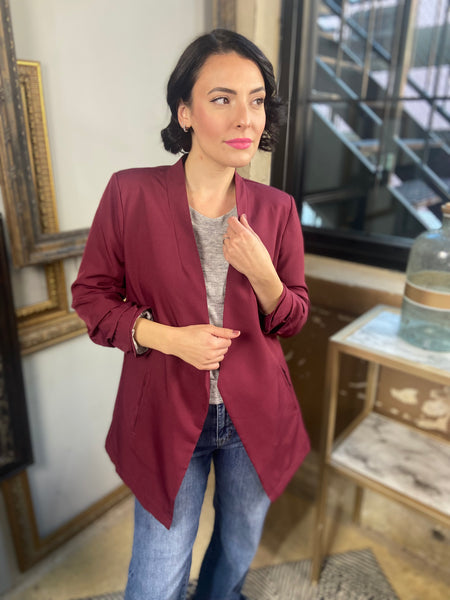 Burgundy colored 3/4 sleeve blazer with open front paired with blue jeans