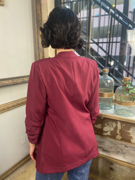 Back view of a burgundy colored 3/4 sleeve blazer