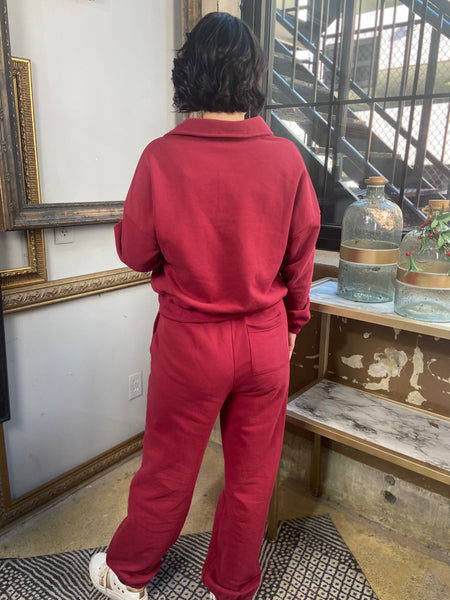 Back view of a burgundy polo style long sleeved sweatshirt with matching drawstring sweatpants