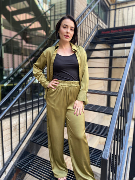 Olive colored satin button down top shown open over a black tank top with matching olive colored satin elastic waisted wide leg pants