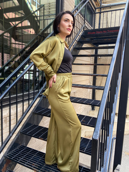 Side view of olive colored satin pants with wide legs and pockets