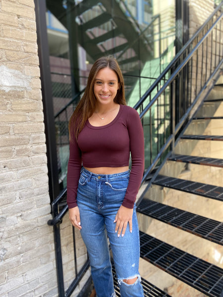 Maroon colored fitted long sleeved cropped top paired with blue jeans