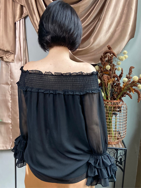 Back view of a black off shoulder dressy blouse with ruffles