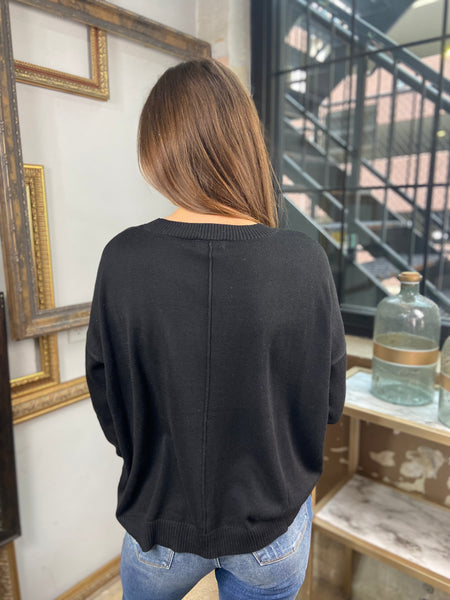 Back view of a black sweater paired with blue jeans