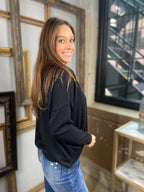 Side view of a black sweater from Blu Pepper with drop shoulders paired with blue jeans