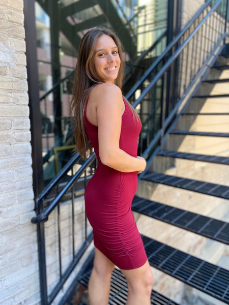 Side view of a Burgundy colored sleeveless bodycon dress