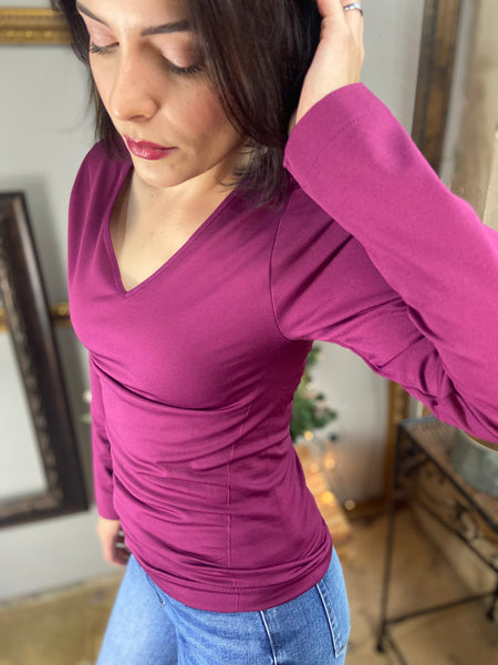 Close up view of a magenta colored fitted fleece lined v neck top