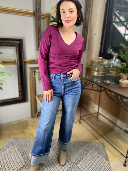 Magenta colored fitted fleece lined v neck top paired with Mica wide leg cuffed blue jeans