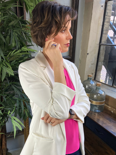 Side view of an ivory blazer with cuffed sleeves and pockets