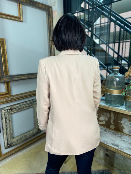 Back view of a light mocha colored blazer with blue jeans