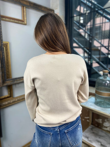 Back view of a light taupe colored sweater paired with blue jeans