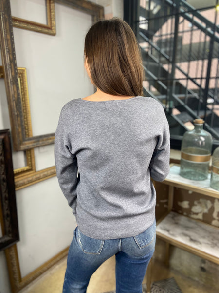 Back view of a grey colored sweater paired with blue jeans