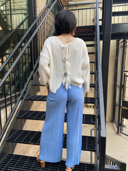 pleated blue pants with drawstring waistband detailing long raw hem light blue lightweight pants back view