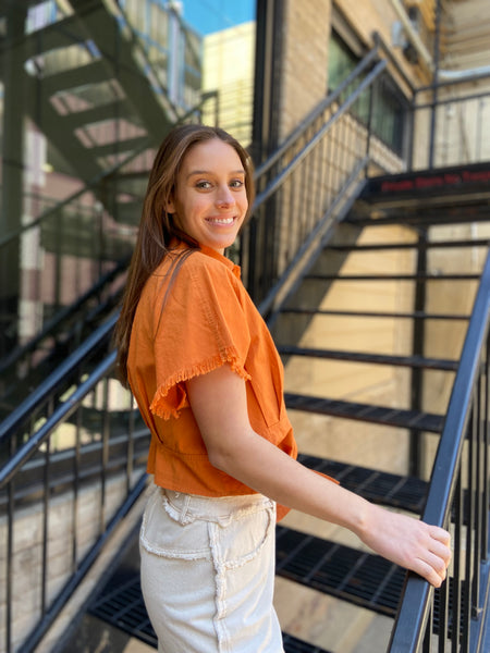 Upgrade your wardrobe with the Juliet Orange Short Sleeve Button Up. This vibrant top features short sleeves with a frayed design and a tie waist for a stylish touch. Made with a cropped cut, this button up delivers a trendy look.