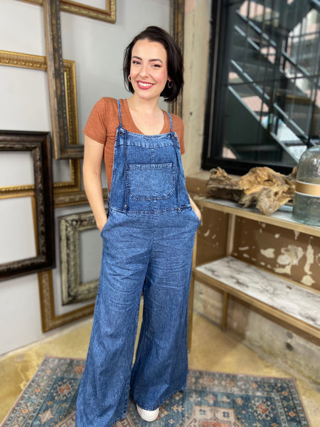 dark wash denim blue overalls jumpsuit wide leg spaghetti straps pockets front and back pose view